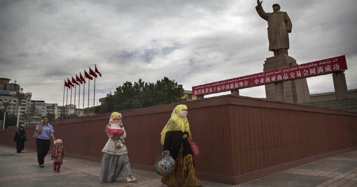 Hai phụ nữ Hồi giáo Duy Ngô Nhĩ đi ngang qua tượng đài Mao Trạch Đông ở thành phố Kashgar, Tân Cương năm 2014. (Ảnh qua IQSoft Software Consultants)