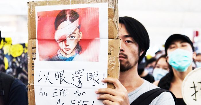 Người biểu tình giơ cao bức tranh vẽ người phụ nữ bị bắn vào mắt trong lúc biểu tình