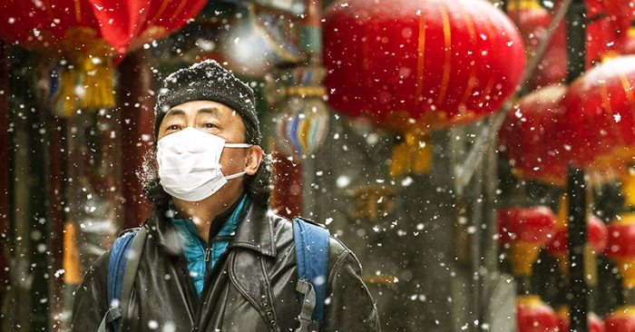 Ngày 5/2, một người đàn ông đeo khẩu trang đi trên đường phố ở Bắc Kinh trong khí trời tuyết lạnh.